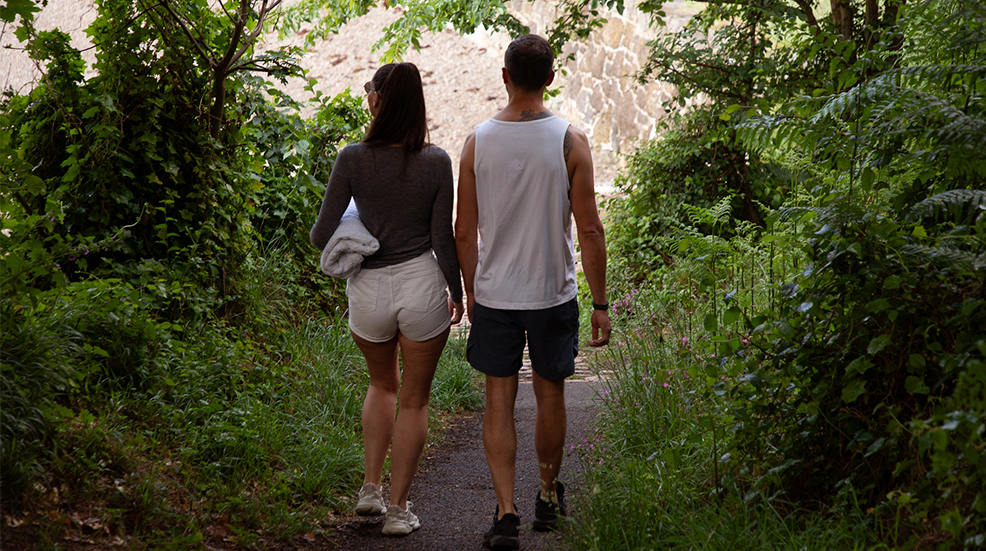 Couple walk hand in hand along a nature trail in Jersey